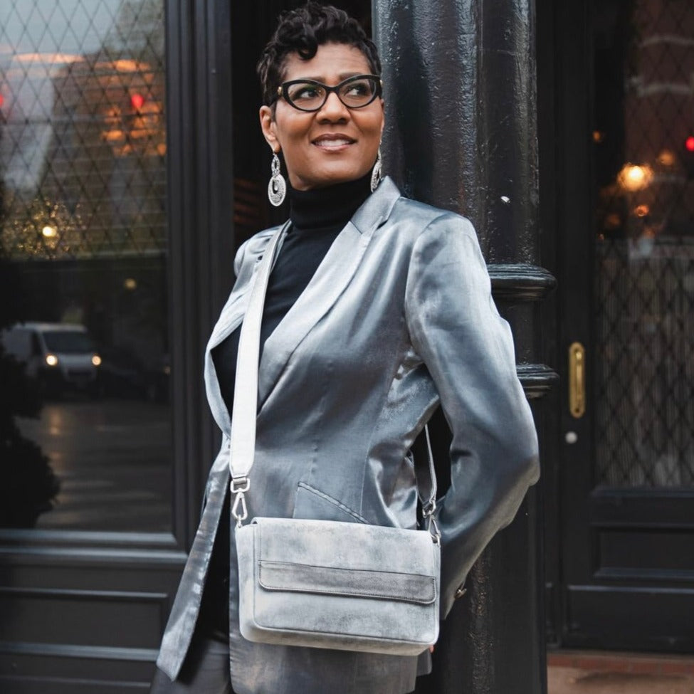 woman holding a laudi vidni prima crossbody in distressed metallic silver leather