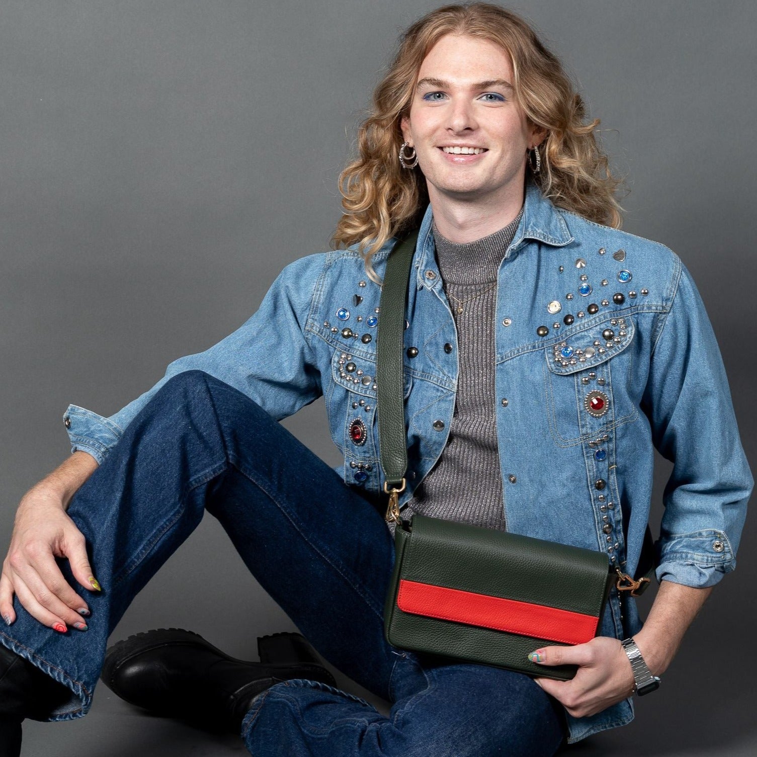 person holding laudi vidni prima crossbody in loden and lipstick leathers