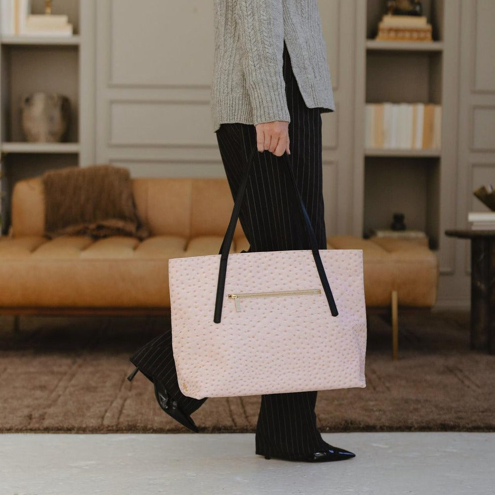 Person holding a textured beige handbag in a living room setting