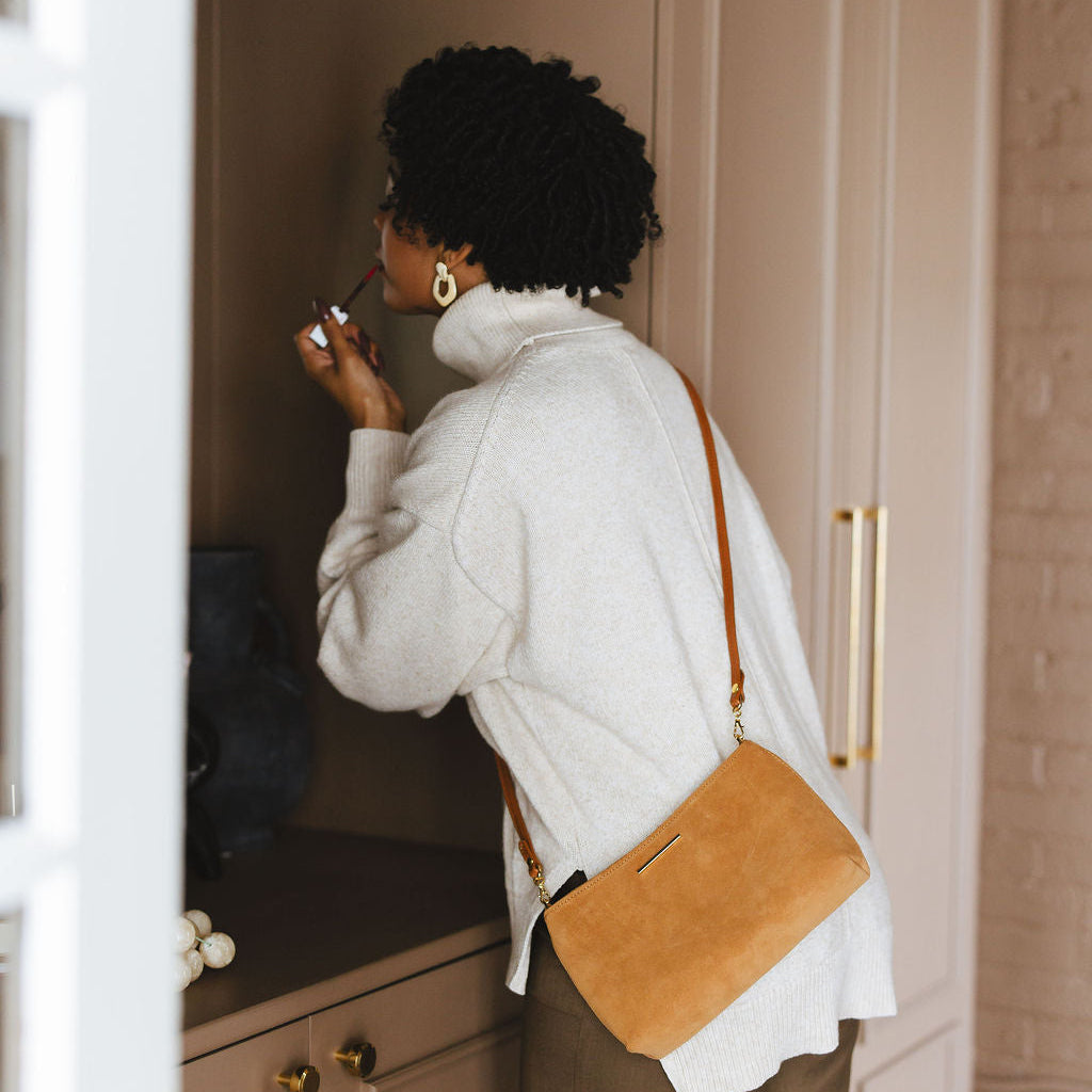 Vivace Crossbody with Leather Strap in Suede model putting lipstick on